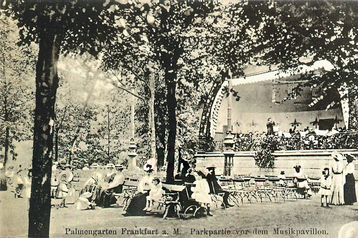 Eine schwarz-weiße Abbildung einer Parkpartie vor dem Musikpavillon. Im Pavillon musiziert ein Orchester. Vor dem Pavillon sind Stühle aufgebaut. Auf den Stühlen sitzen Menschen in altertümlicher Kleidung.